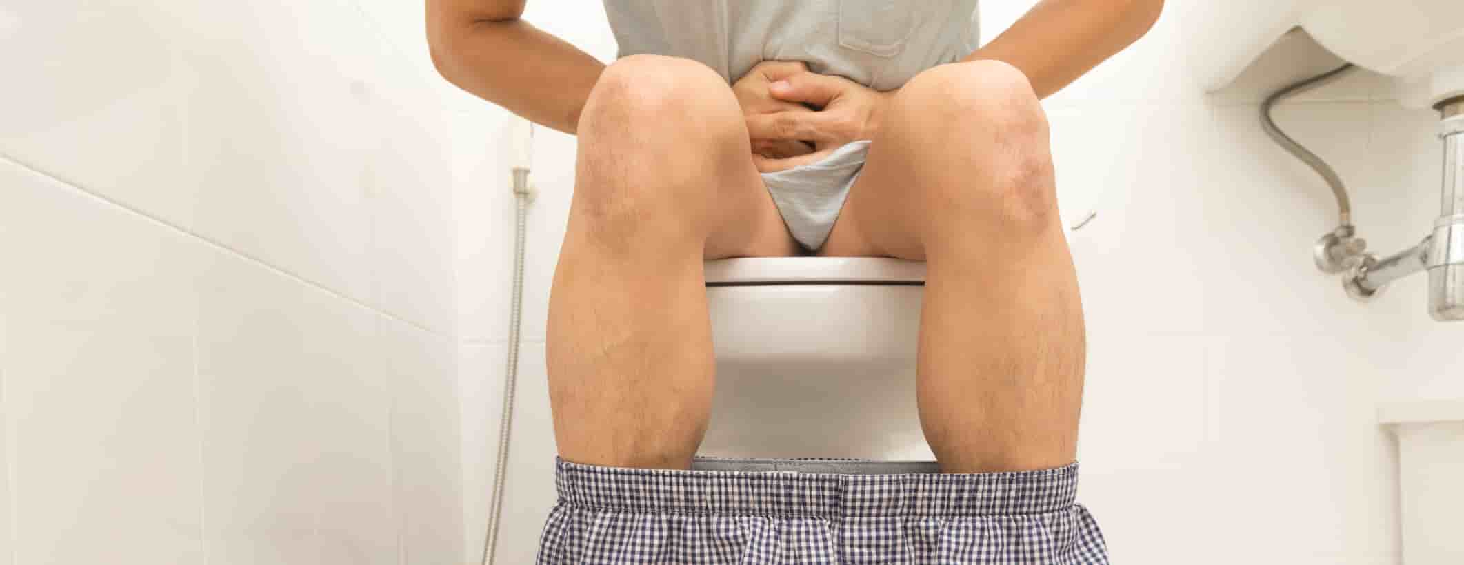 Person sitting with stomach ache and diarrhoea, sitting on a compost toilet